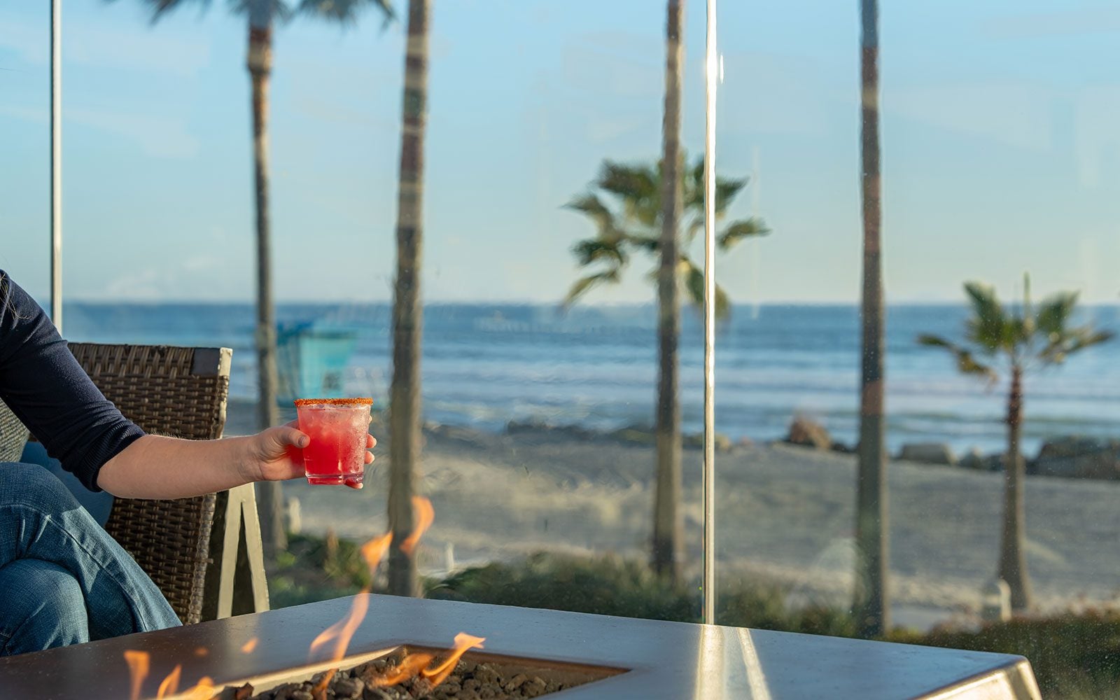 Hand holding a cocktail by the fire