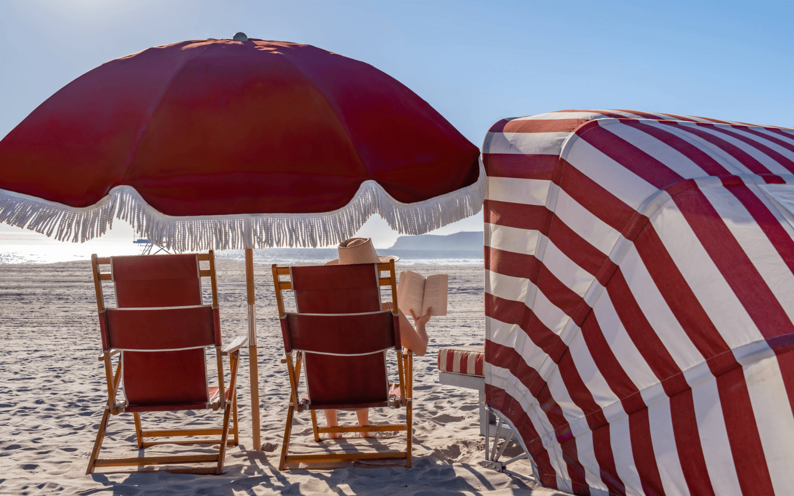 Woman reading a book under an umbrella on the beach
