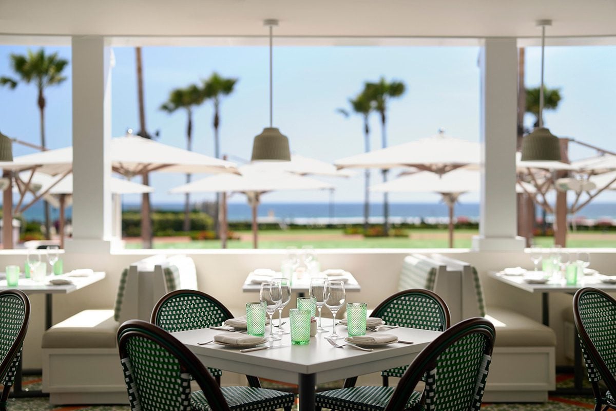 a table with cutlery and glasses set overlooking umbrellas and the ocean